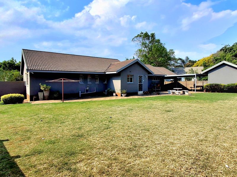 Spacious rear garden featuring a well-maintained lawn, paved patio area, and a detached garage, providing ample outdoor space for recreation.