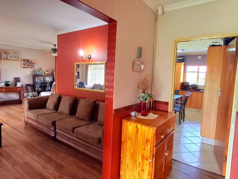 Open plan living area featuring laminate flooring, a ceiling fan, and a direct view into the adjacent kitchen space.