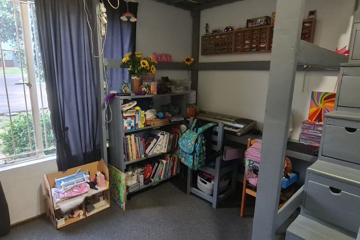 A bedroom featuring a built-in loft bed structure with integrated staircase storage and security bars on the window.