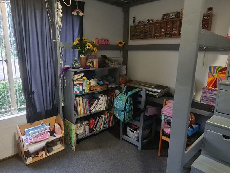 A bedroom featuring a built-in loft bed structure with integrated staircase storage and security bars on the window.