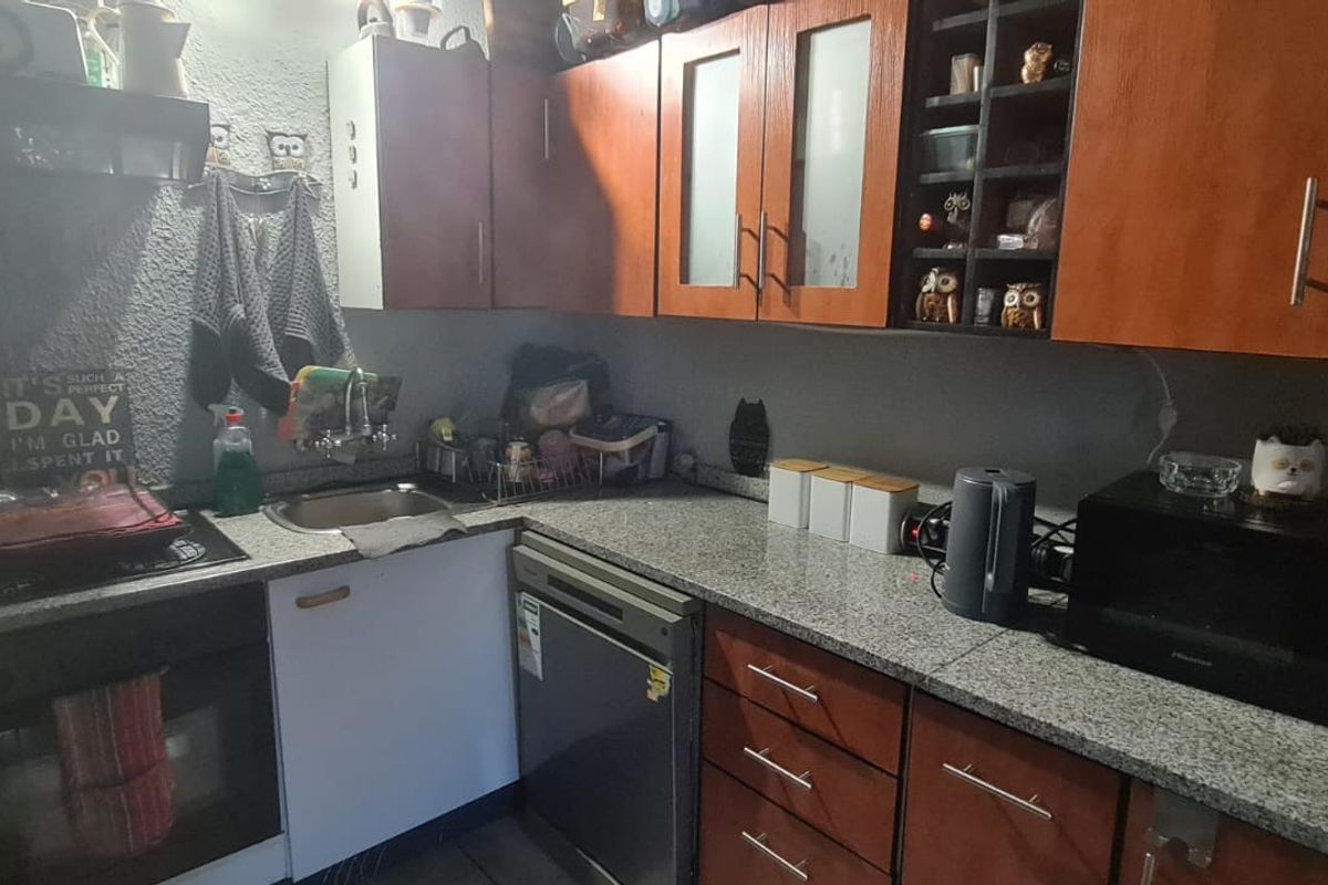 A functional kitchen featuring wood-finish cabinetry, granite countertops, built-in oven, hob, and integrated dishwasher, providing a practical workspace for daily cooking.