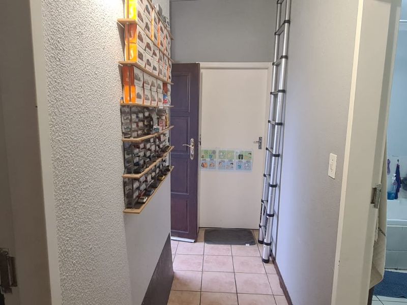 A functional hallway connecting interior spaces, featuring tiled flooring and access to a bathroom.