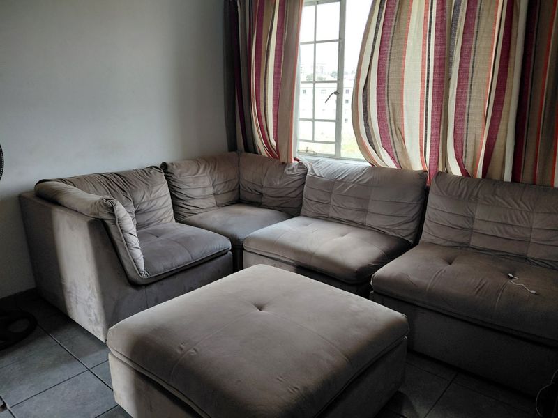 A living room area featuring tiled flooring and a window with grid detailing, providing natural light to the space.