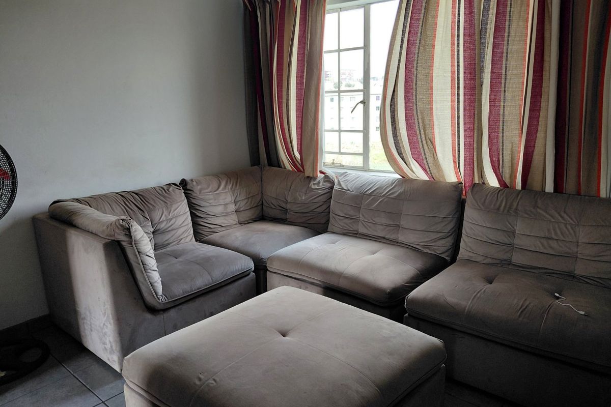 A living room area featuring tiled flooring and a window with curtains.