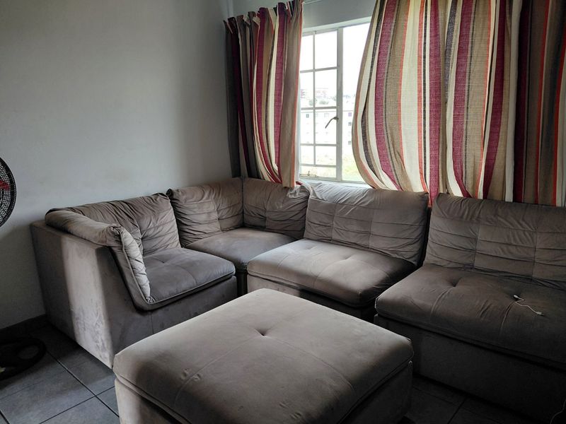 A living room area featuring tiled flooring and a window with curtains.