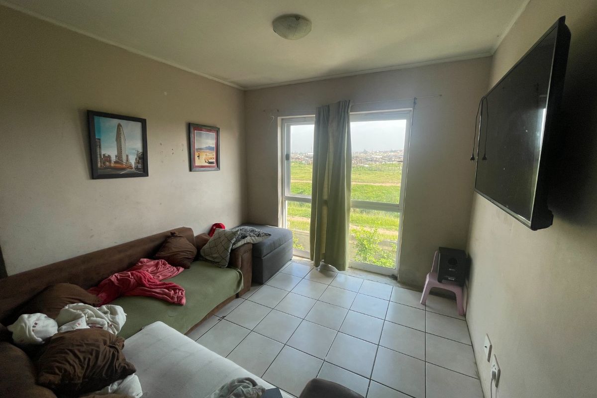A living room featuring tiled flooring and a sliding glass door providing natural light and access to an outdoor view.