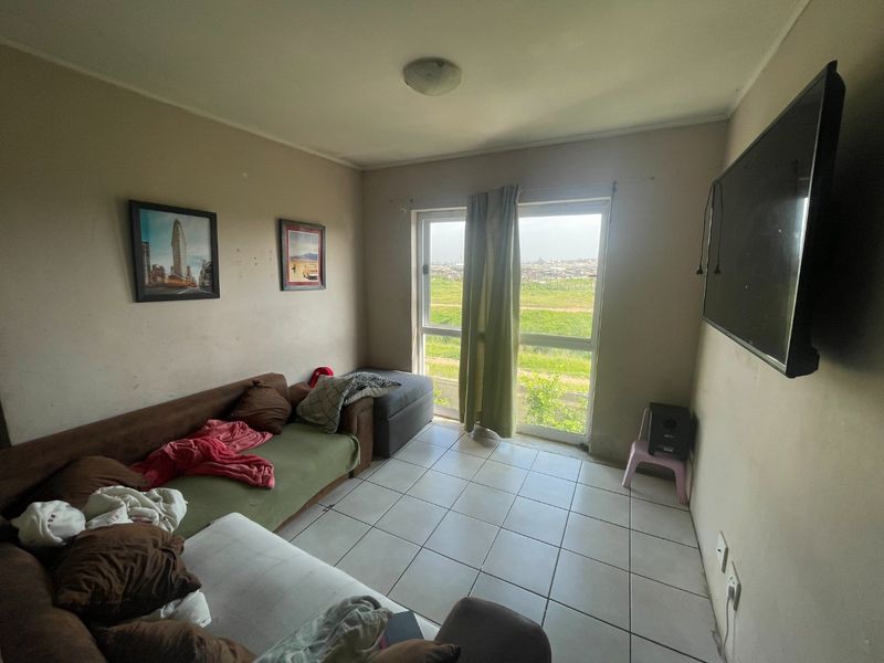 A living room featuring tiled flooring and a sliding glass door providing natural light and access to an outdoor view.