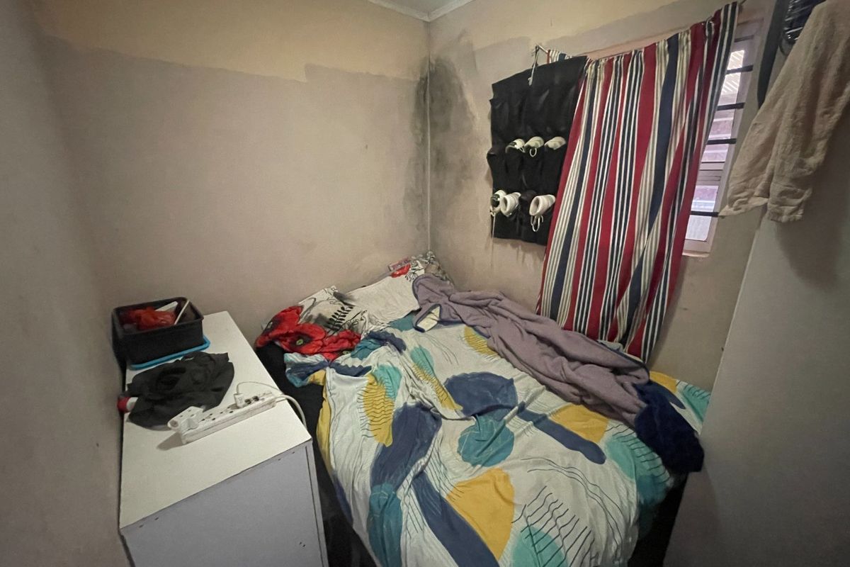 A compact bedroom featuring a window and wall surfaces requiring maintenance and cosmetic repair.