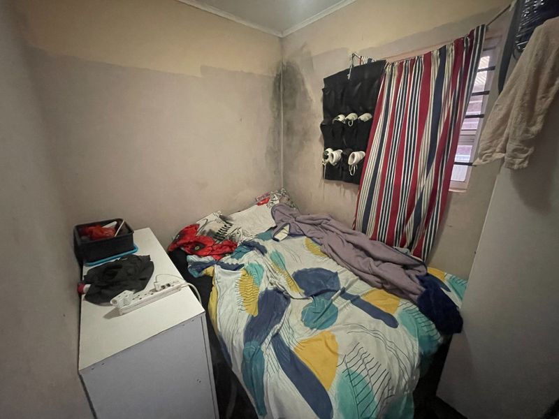 A compact bedroom featuring a window and wall surfaces requiring maintenance and cosmetic repair.