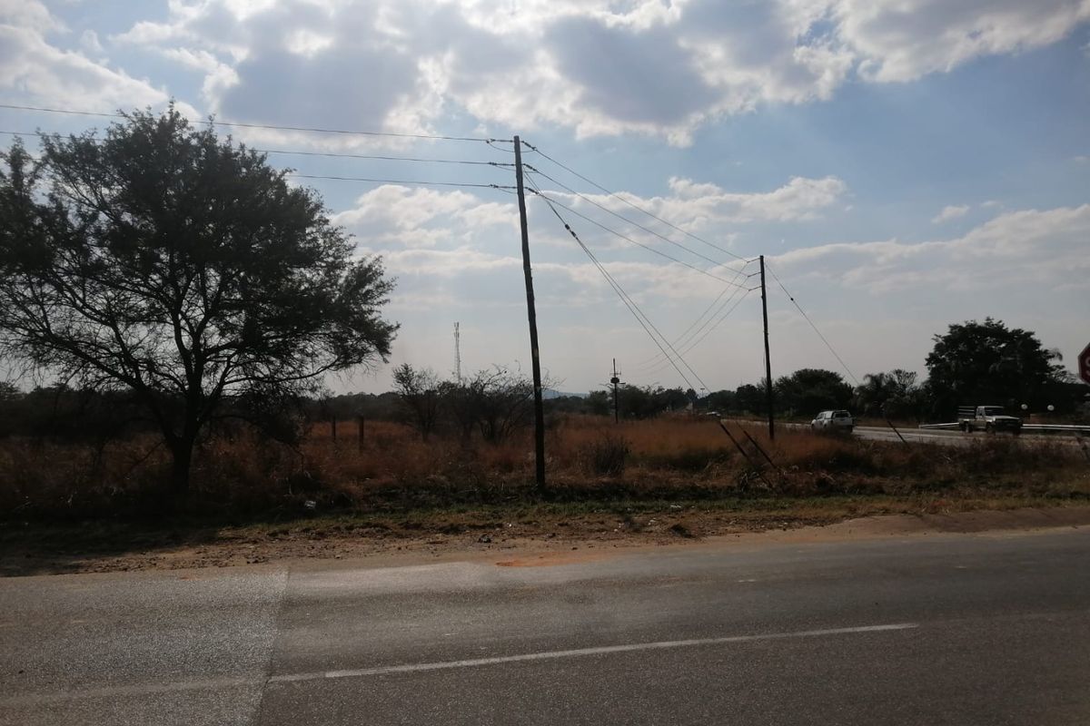 A view of the property frontage from the adjacent asphalt road, featuring utility poles and overhead power lines.