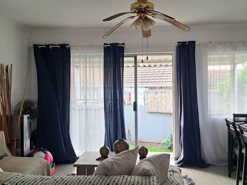 Open plan living and dining area featuring tiled flooring, a ceiling fan, and sliding glass doors providing access to the rear patio.