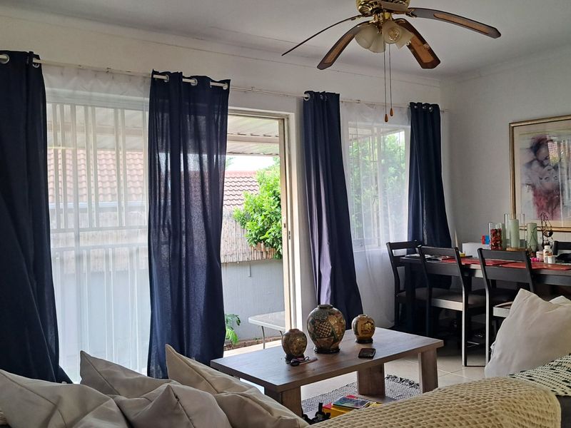 Open-plan living and dining area featuring tiled flooring, a ceiling fan, and sliding glass doors providing access to the outdoor space.