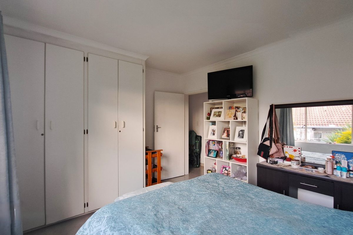 A functional bedroom featuring built-in cupboards and coving, offering a practical layout with natural light.