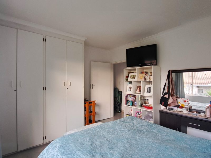 A functional bedroom featuring built-in cupboards and coving, offering a practical layout with natural light.