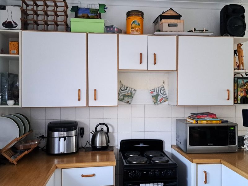 A functional kitchen featuring white cabinetry, laminate countertops, and a tiled backsplash, providing a practical workspace with a classic layout.