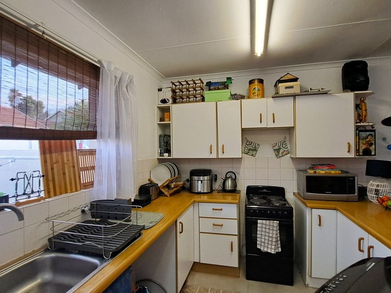 A functional kitchen featuring laminate countertops, tiled splashbacks, and ample built-in cabinetry, providing a practical workspace with a classic layout.