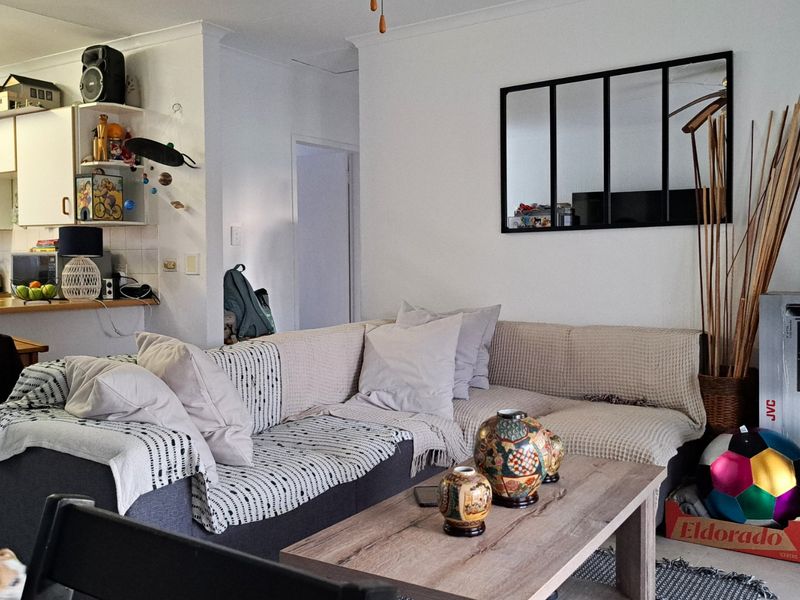 Open plan living area featuring a functional kitchen with cabinetry and tiled backsplash, seamlessly connected to the main lounge space.