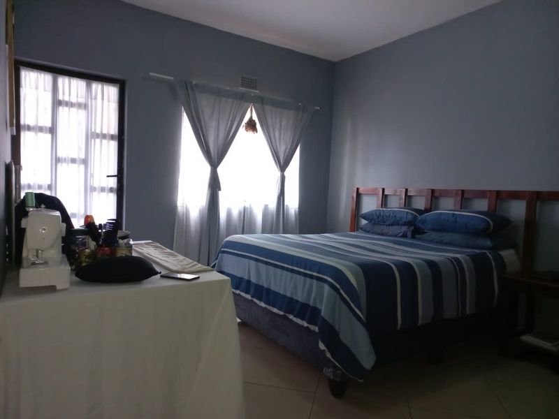 A bedroom featuring tiled flooring, natural light from a window, and access to an exterior door.