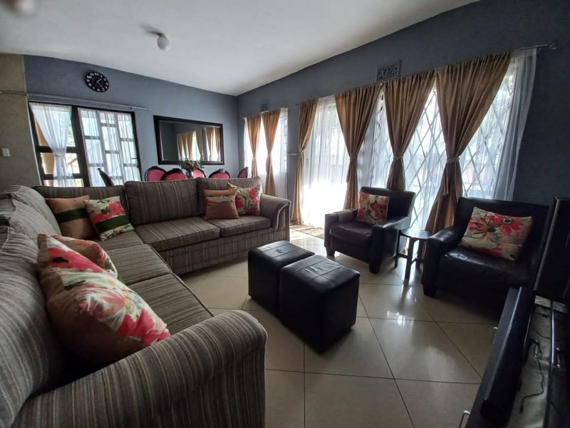 Spacious living room featuring large sliding doors with security gates and neutral tiled flooring, offering a bright and functional layout.