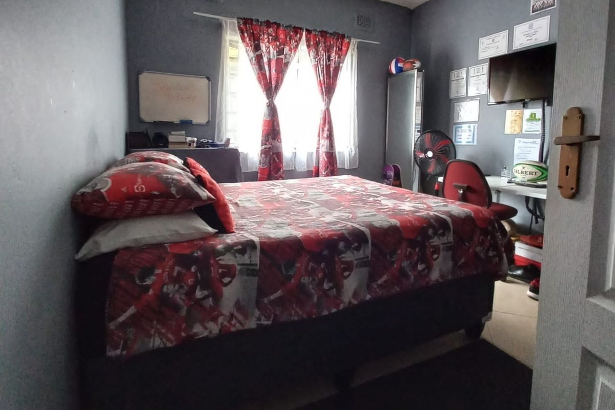 A bedroom featuring dark painted walls, a window with curtains, and a standard interior door.