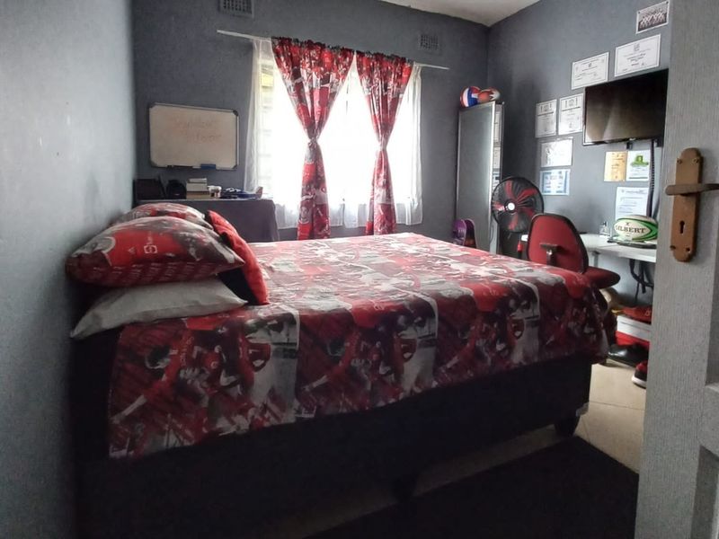 A bedroom featuring dark painted walls, a window with curtains, and a standard interior door.