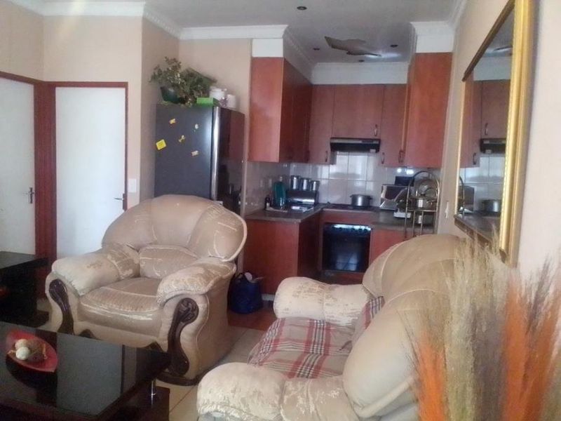 Open plan living area featuring a compact kitchen with built-in cabinetry, oven, and hob, showing signs of ceiling damage.