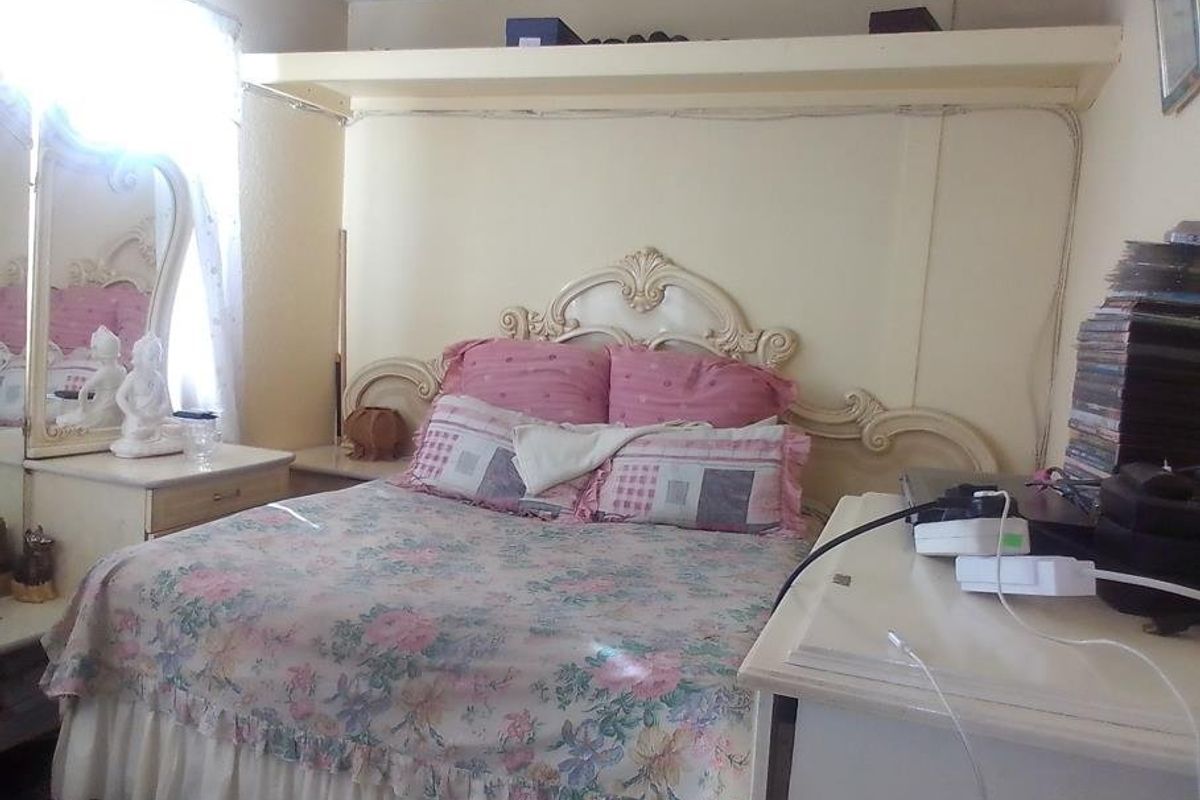 A bedroom featuring a built-in shelf above the bed area, with visible electrical wiring along the wall.
