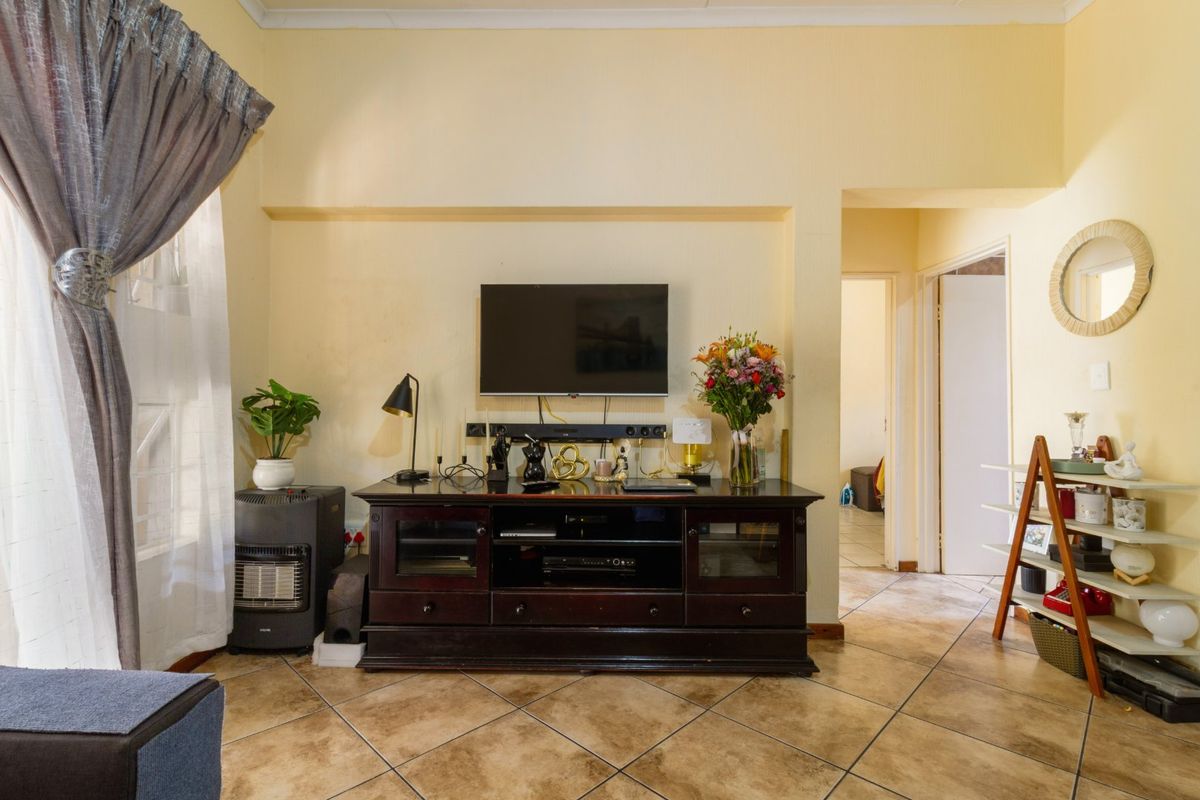 A living room featuring tiled flooring and neutral wall finishes, providing a functional space with access to adjacent rooms.