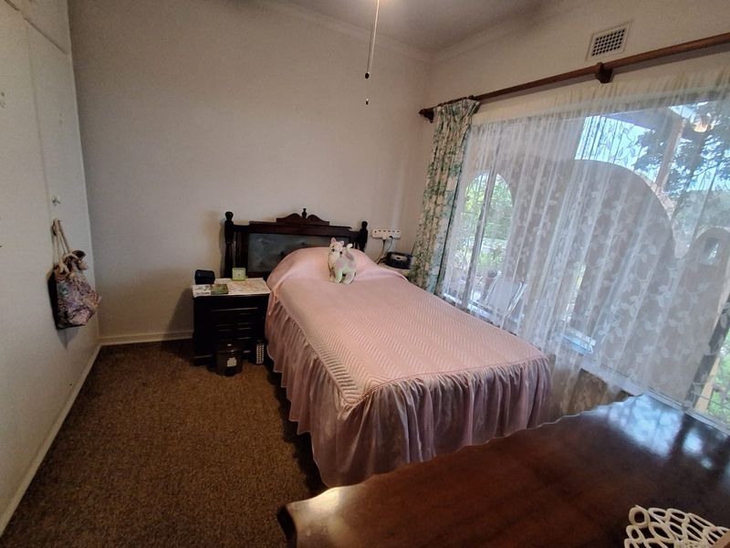 A bedroom featuring carpet flooring, a built-in wardrobe, and a ceiling fan, with natural light provided by a large window.