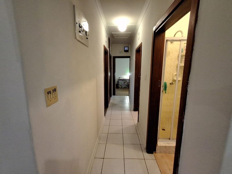 A functional hallway featuring tiled flooring, providing access to multiple rooms including a bathroom with a shower enclosure.