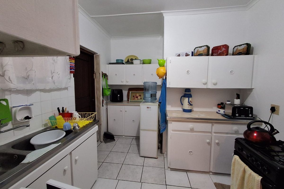 Functional kitchen featuring white built-in cabinetry, tiled splashbacks, and tiled flooring, offering a practical layout with ample storage space.