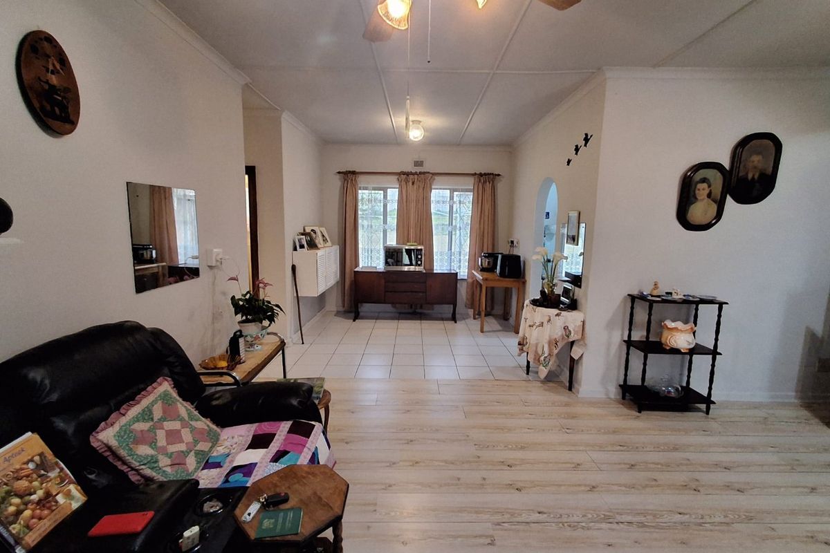 A spacious living area featuring a mix of laminate and tiled flooring, a ceiling fan, and an open archway leading to an adjacent space.