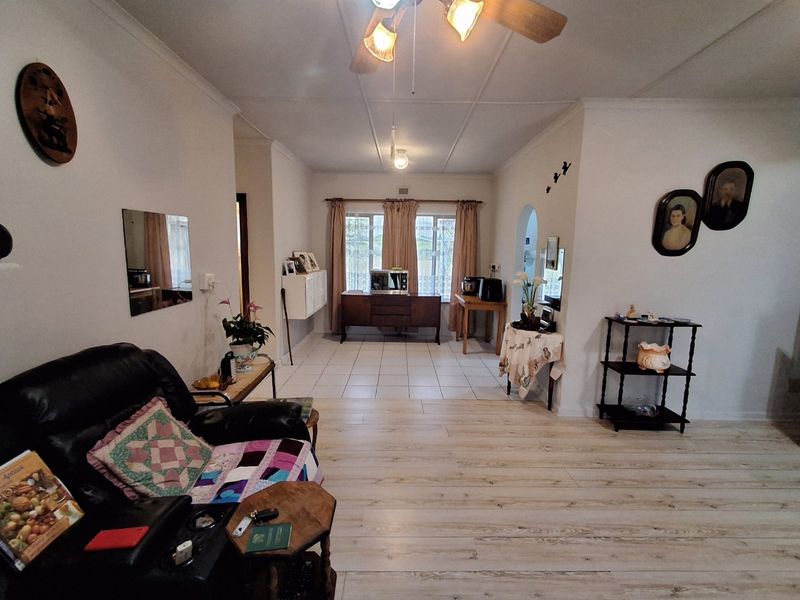 A spacious living area featuring a mix of laminate and tiled flooring, a ceiling fan, and an open archway leading to an adjacent space.