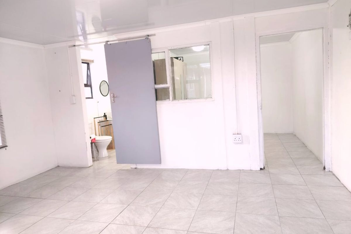 An empty living area featuring tiled flooring, a sliding door, and an internal window, providing a blank canvas for interior design.