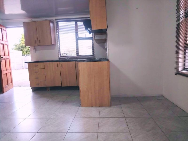 A functional kitchen featuring laminate cabinetry, stone countertops, and tiled flooring, offering a clean and practical space ready for modern updates.