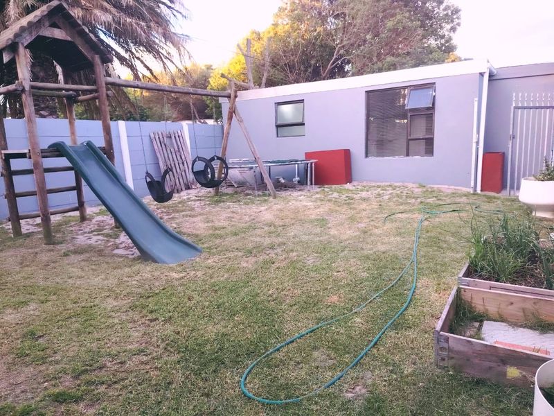 Rear garden area featuring a lawn, boundary wall, and security gate access, providing a functional outdoor space for the property.
