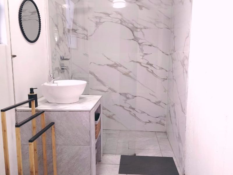 Modern bathroom featuring a walk-in shower with marble-look wall tiles, a vessel sink vanity, and neutral floor tiling.