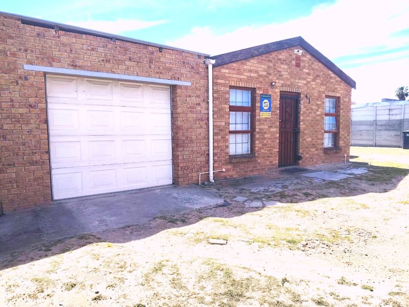 Front exterior view of a face brick house featuring a single garage, security gate, and an open yard area.