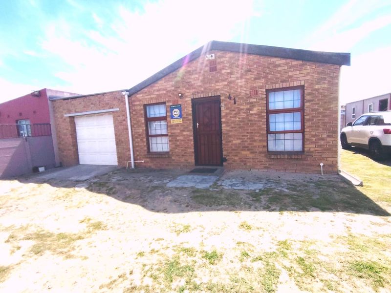 Front elevation of a face brick house featuring a single garage, security gate, and established security alarm system.
