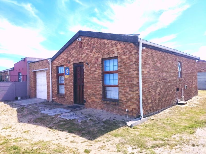 Front view of a single-story face-brick house featuring a single garage, security gate, and established gutter system.