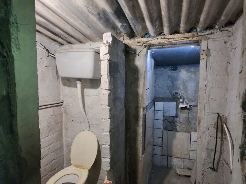 A basic bathroom space featuring a toilet and exposed brickwork, requiring significant renovation and finishing to meet modern standards.