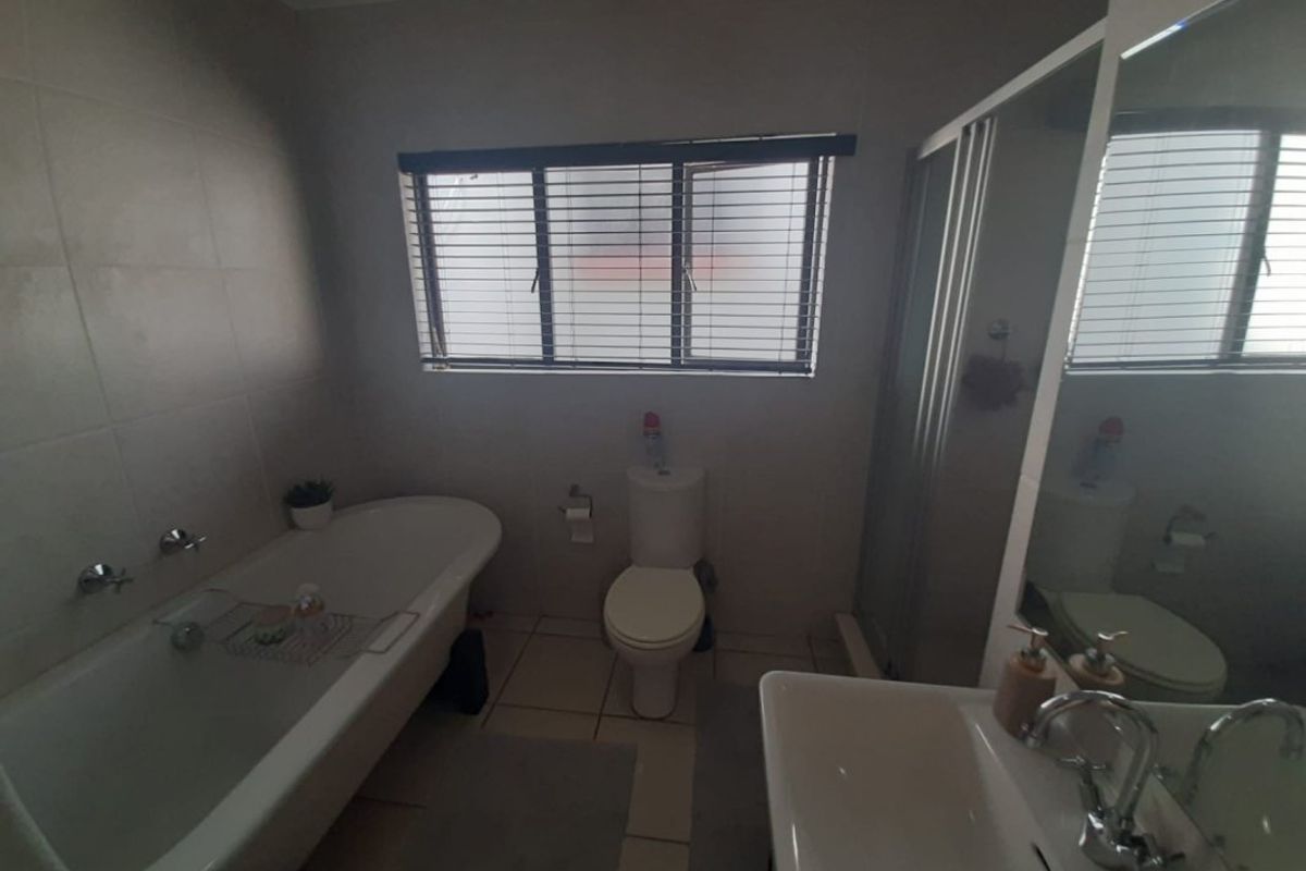 A functional bathroom featuring a freestanding bathtub, separate shower enclosure, toilet, and vanity basin with tiled finishes throughout.