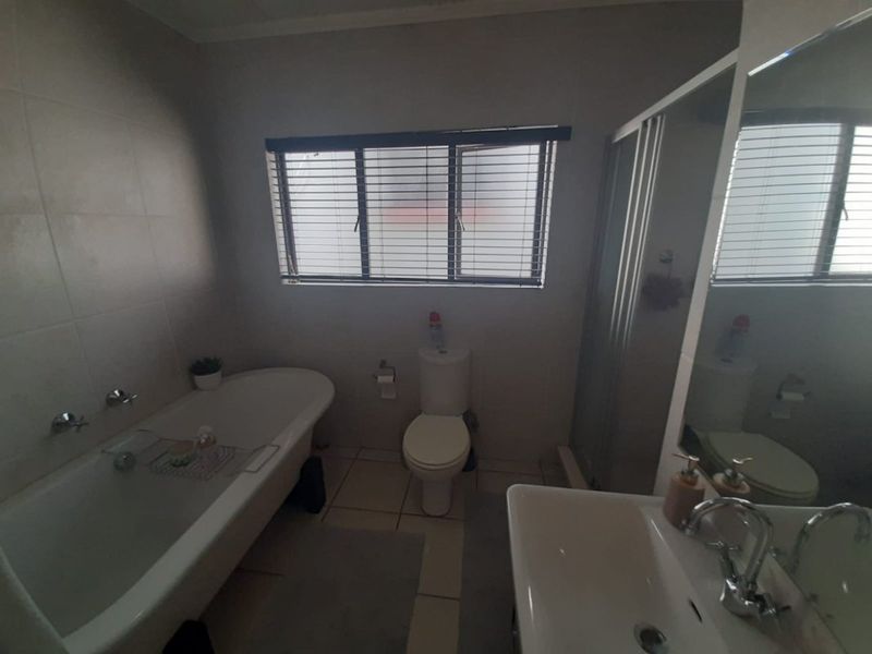 A functional bathroom featuring a freestanding bathtub, separate shower enclosure, toilet, and vanity basin with tiled finishes throughout.