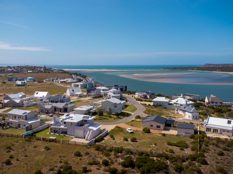 An aerial view of a coastal residential estate situated near an estuary, showcasing the surrounding landscape and neighborhood layout.