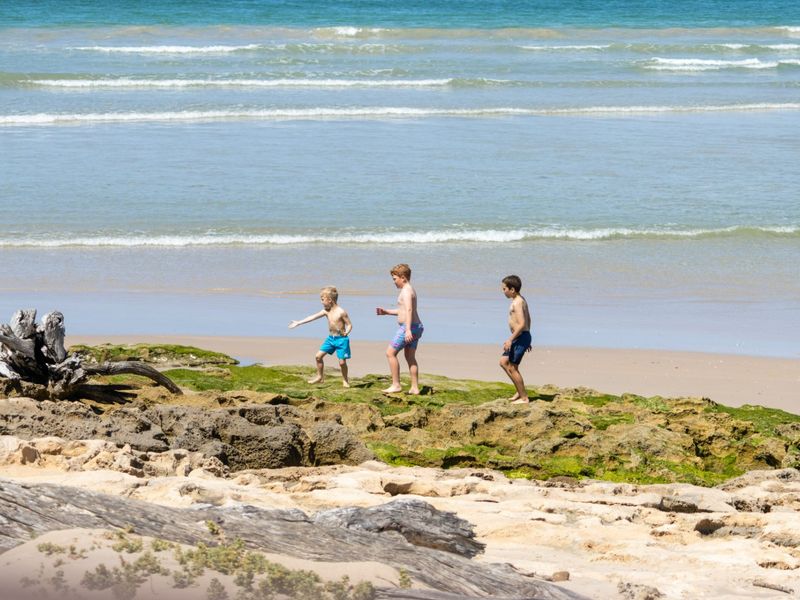 A scenic view of the coastal shoreline featuring natural rock formations and sandy beach access.