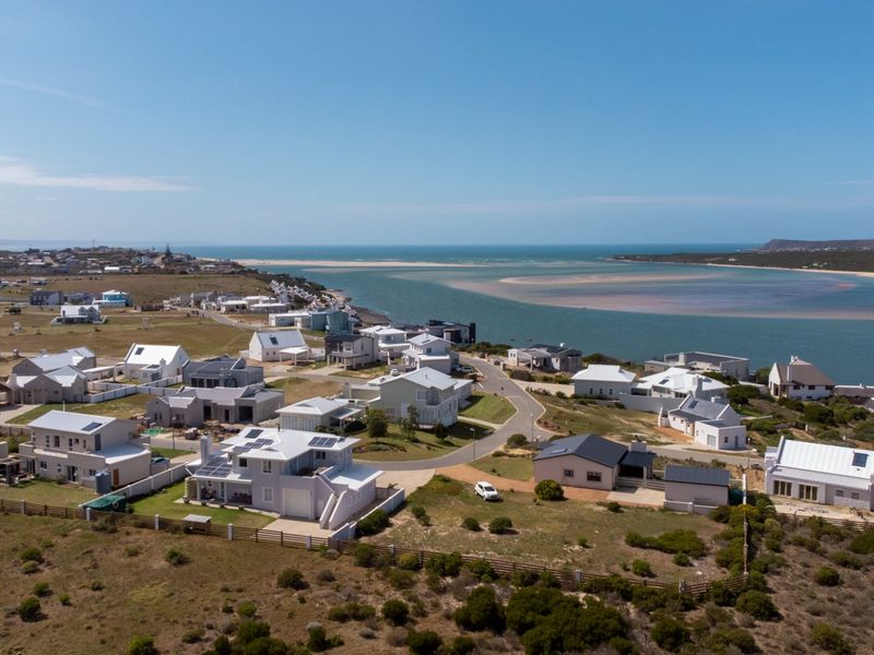 Aerial view of a coastal residential estate situated near an estuary, showcasing the surrounding landscape and neighborhood layout.