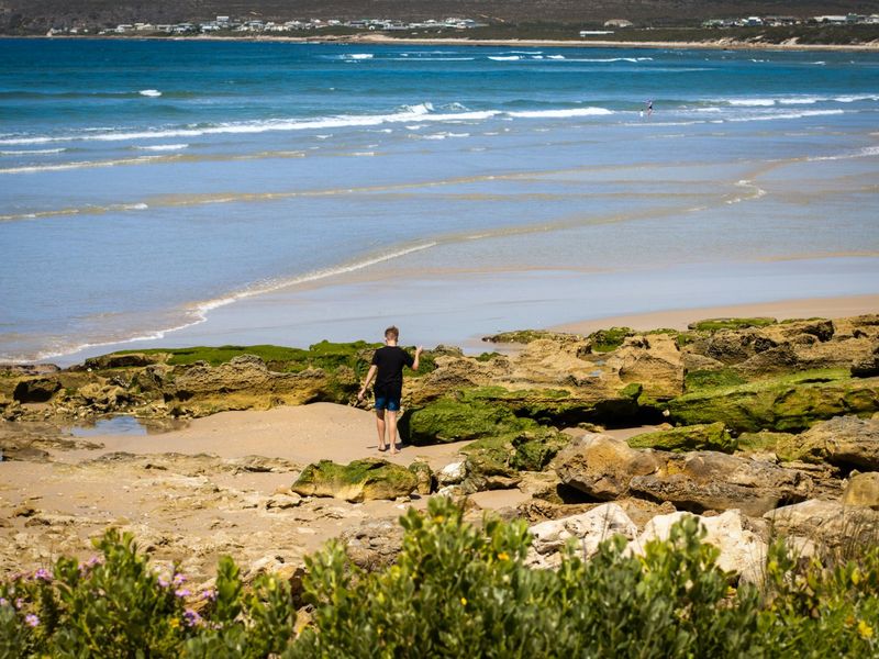 A scenic coastal view overlooking the sandy beach and ocean, highlighting the natural landscape and rocky shoreline.