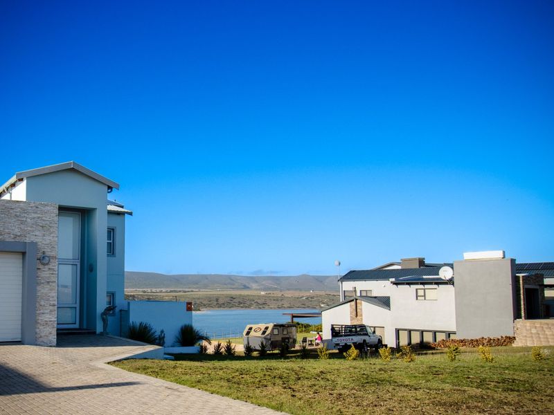 Front view of a modern residential property featuring stone cladding, a paved driveway, and a garage, set against a scenic landscape.