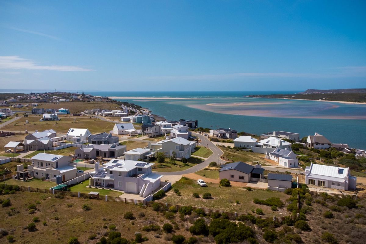 An aerial view of a coastal residential estate situated near an estuary, showcasing the surrounding landscape and neighborhood layout.