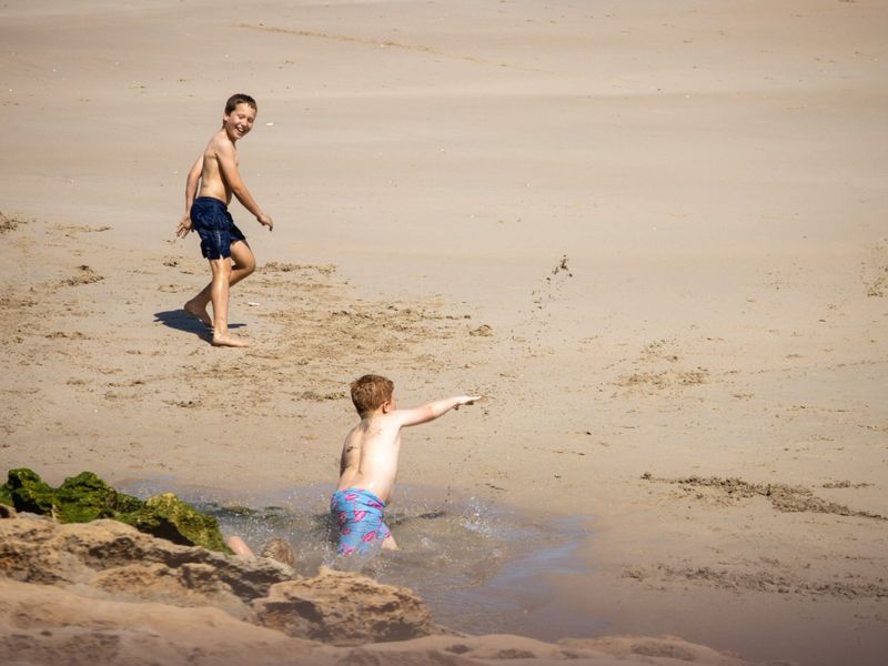 A photograph showing people on a sandy beach, which does not provide information regarding the residential land property.